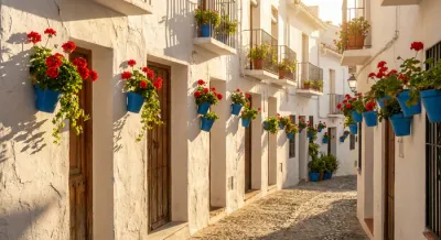 Ruelle fleurie typique avec géraniums rouges et murs blancs à Frigiliana