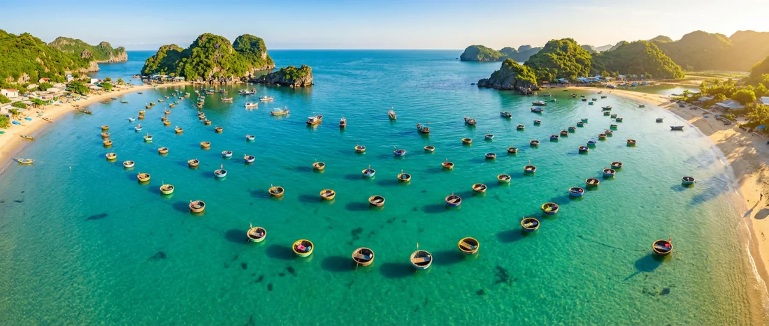 Vue aérienne par drone de bateaux paniers traditionnels vietnamiens sur une eau turquoise cristalline.