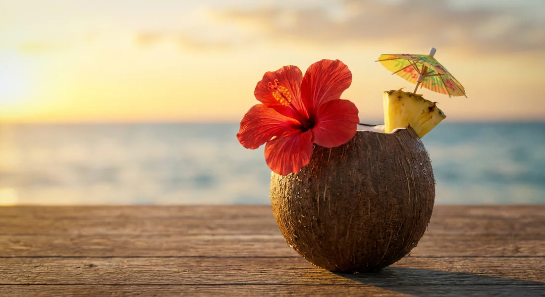 Cocktail tropical festif servi dans une noix de coco sur la plage.