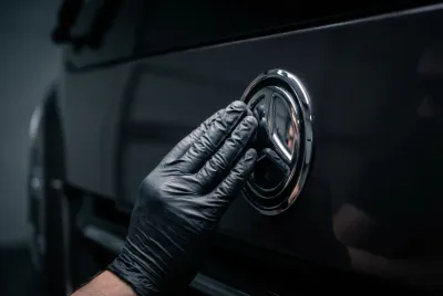 Gros plan d'une main gantée qui lustre un détail chromé sur la carrosserie d'un camping-car, créant un reflet parfait.